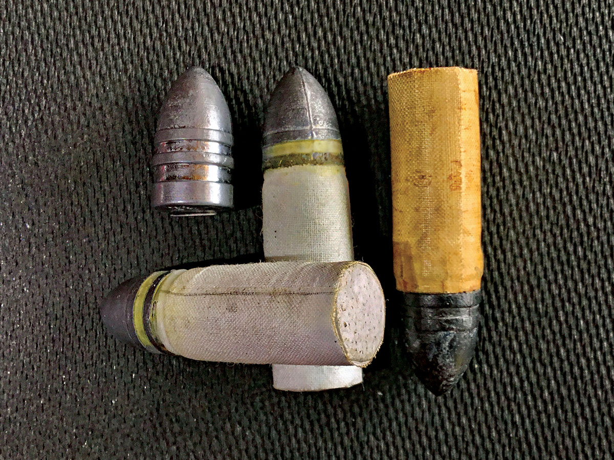 From left to right: a naked bullet from the original Sharps mould. Next to it is one of our new linen cartridges tilted upward to show the seam and the paper base, followed by another one of our linen cartridges lying flat. On the far right is an original Sharps Company cartridge for comparison. Note that the linen is “choked” into the bottom groove of the bullets, in accordance with a late-war regulation, to help keep the powder from leaking  out around the bullet.